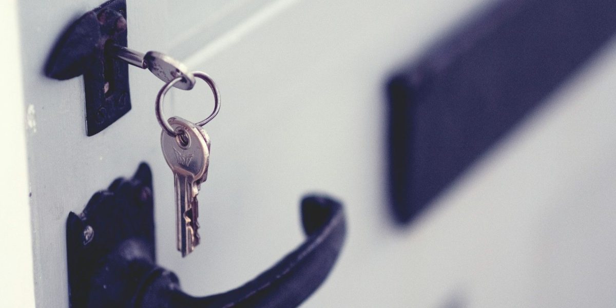 Flat image_Housekeys are hanging from a keyhole on a black and white door in the NH Seacoast housing market