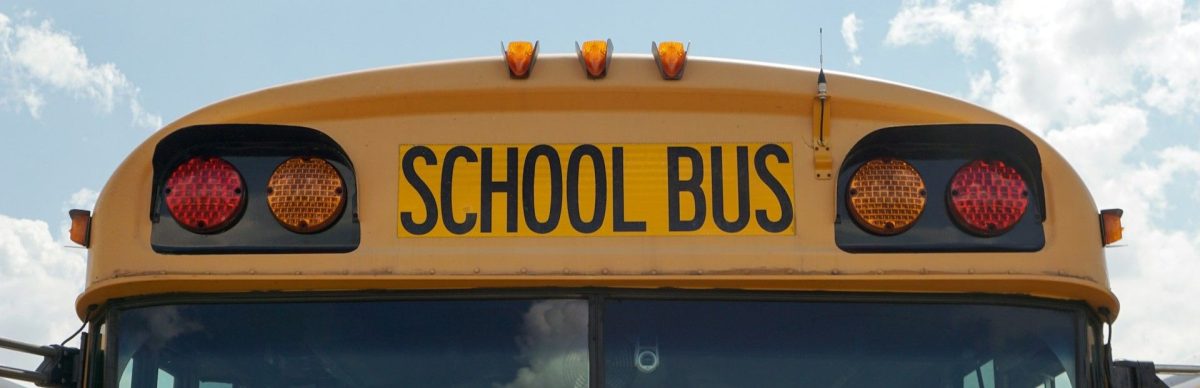 The front of a yellow school bus against a bright blue sky showing how NH towns use property taxes